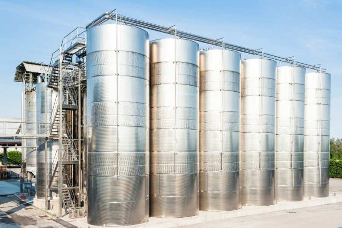 Une grande cuve inox cylindrique installée en extérieur au sein d'une exploitation agricole ou industrielle.