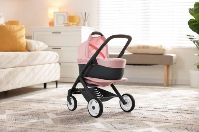 Une poussette landau rose pour bébé est installée dans un salon confortable, suggérant la fin d'une promenade et le début de la sieste.