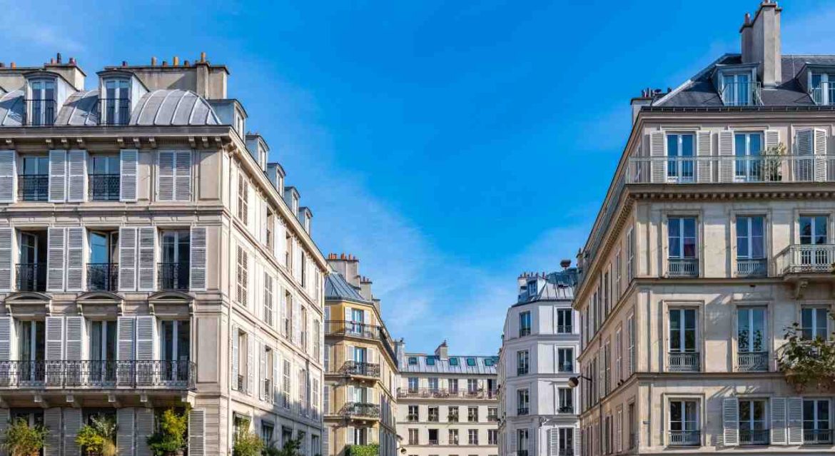 Façades d'immeubles haussmanniens en pierre de taille illustrant l'attraction centre ville prix m2 sous un ciel bleu.
