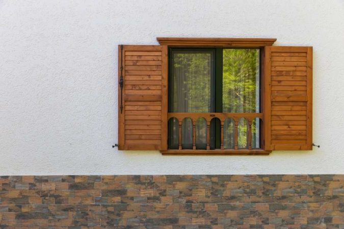 Des volets en bois élégants installés sur une façade blanche lumineuse