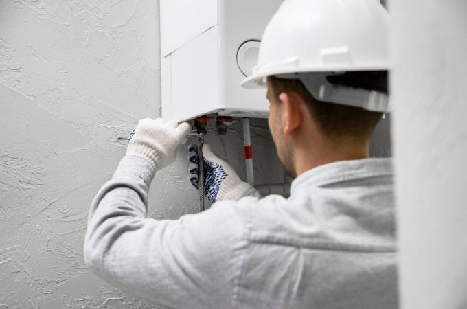 Un technicien en casque de chantier intervient sur une chaudière lors d'une préparation dépannage urgence chauffage.
